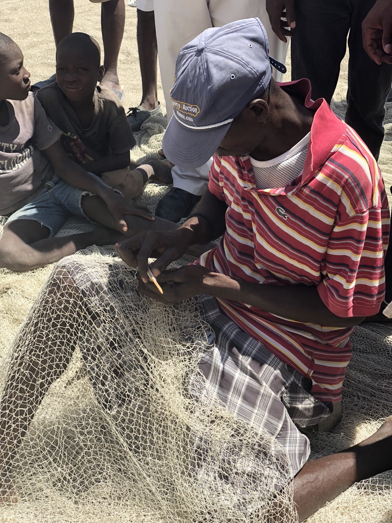 Haitian man fixing fishing net
