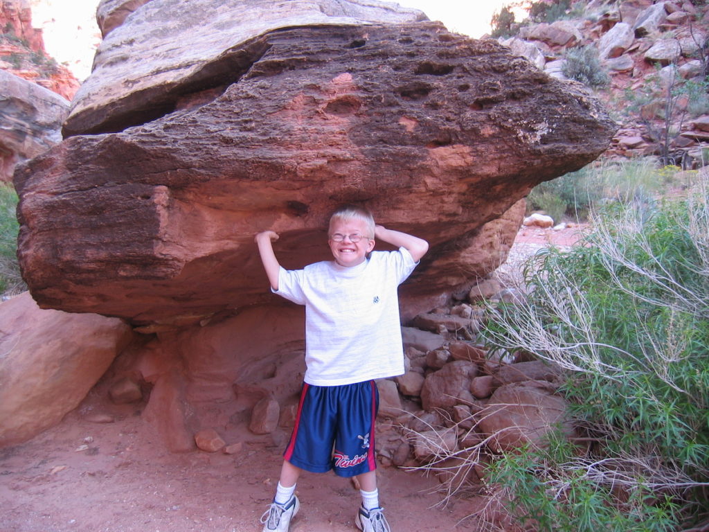 boy with down syndrome pretending to lift a big boulder overhead