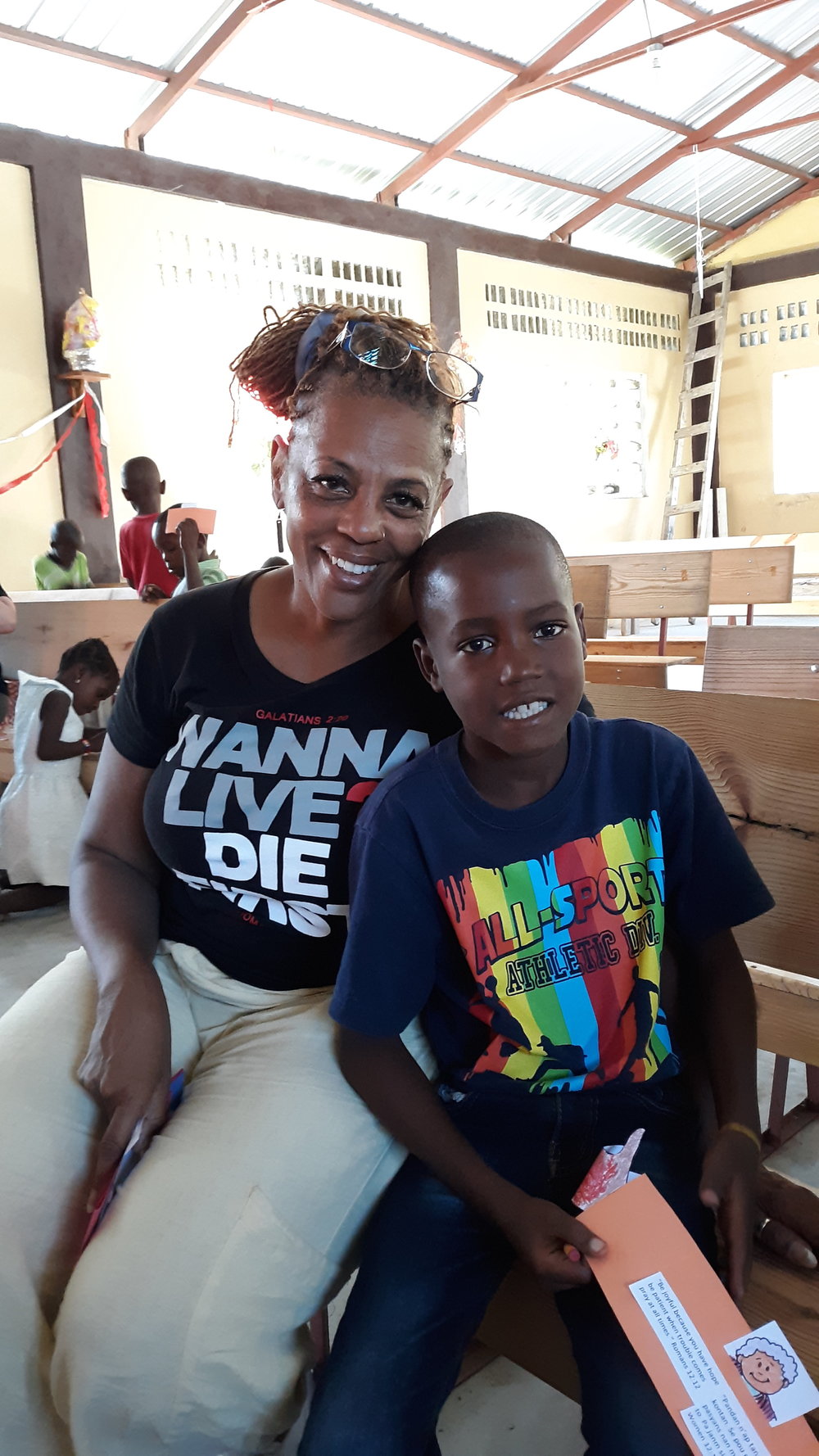 Woman with Haitian boy sitting on bench smiling