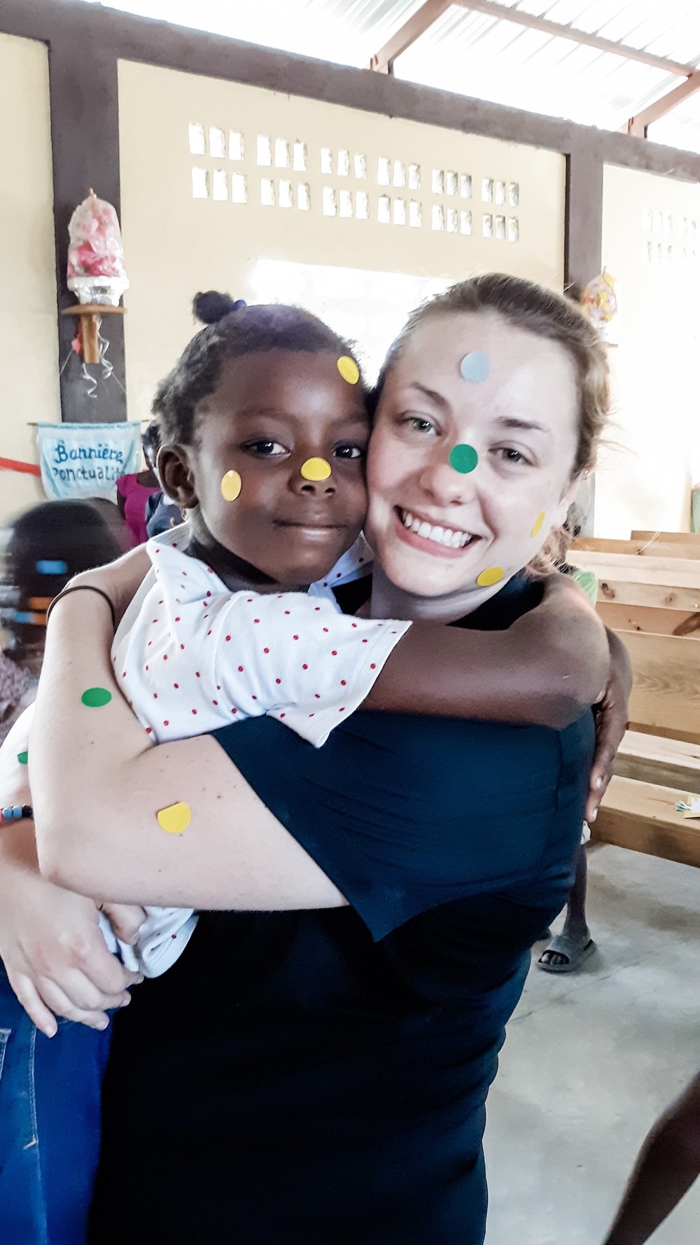 woman holding girl with stickers on faces