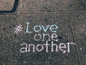 "Love one another" written in chalk on concrete