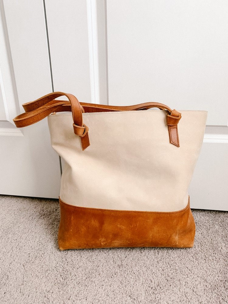 tan and cream leather tote bag sitting on floor