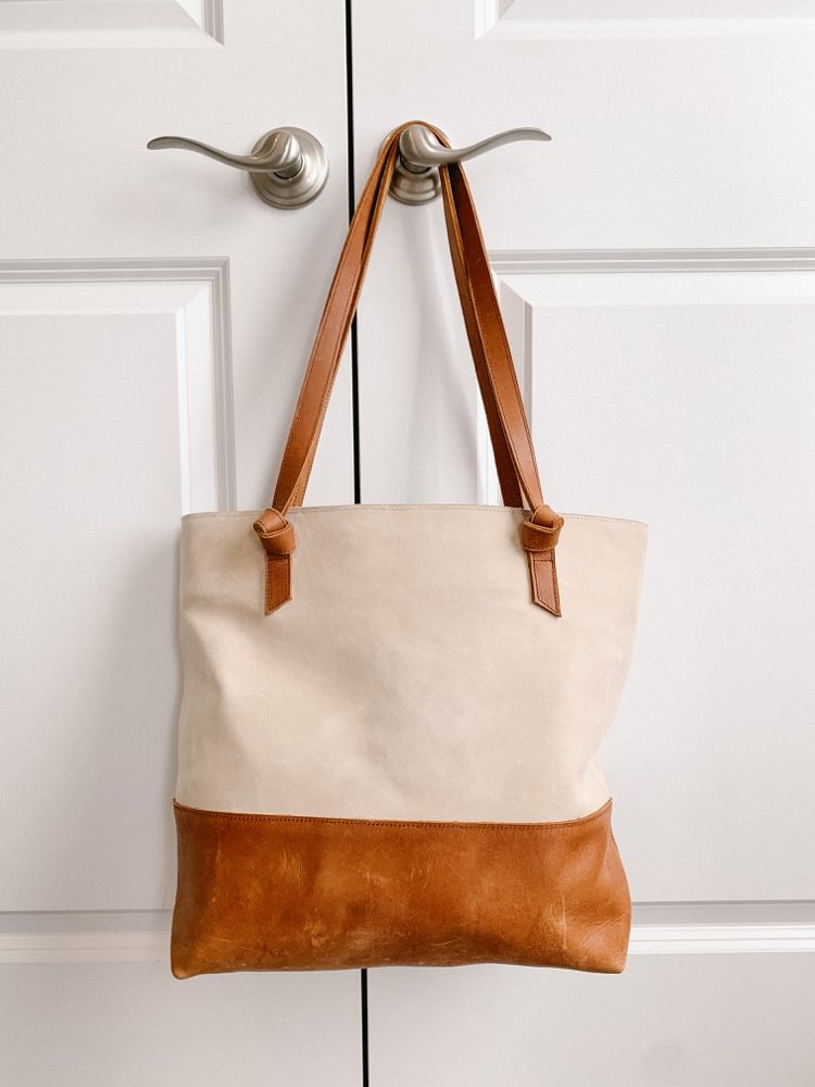 tan and cream leather tote bag hanging from door