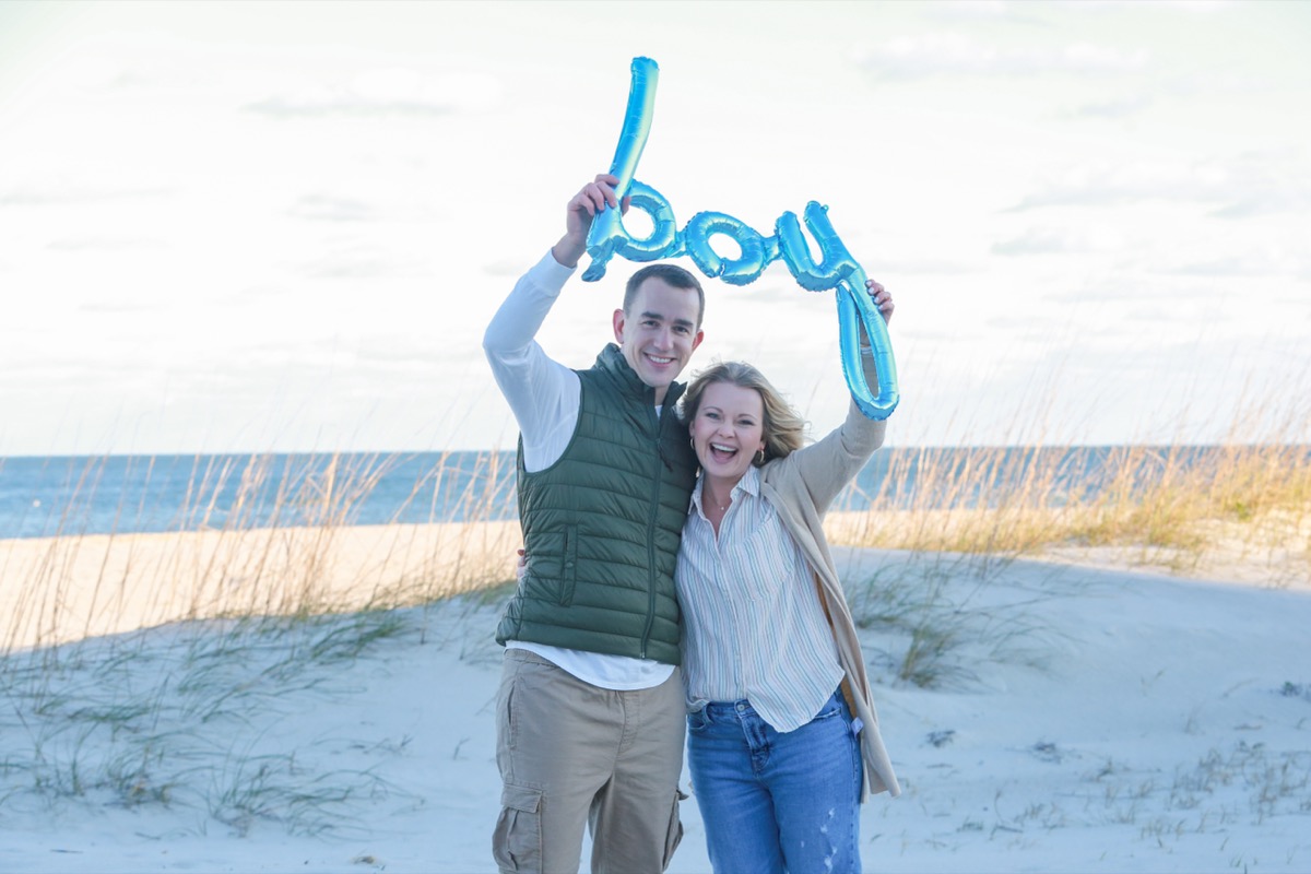 man and woman holding blue "boy" balloon