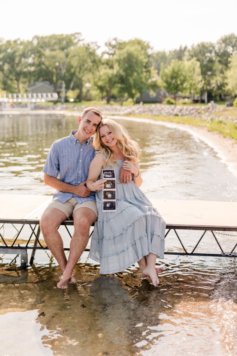 man and woman sitting on dock holding baby ultrasound picture